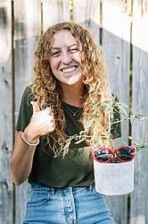 年轻女子在篱笆前捧着一盆植物